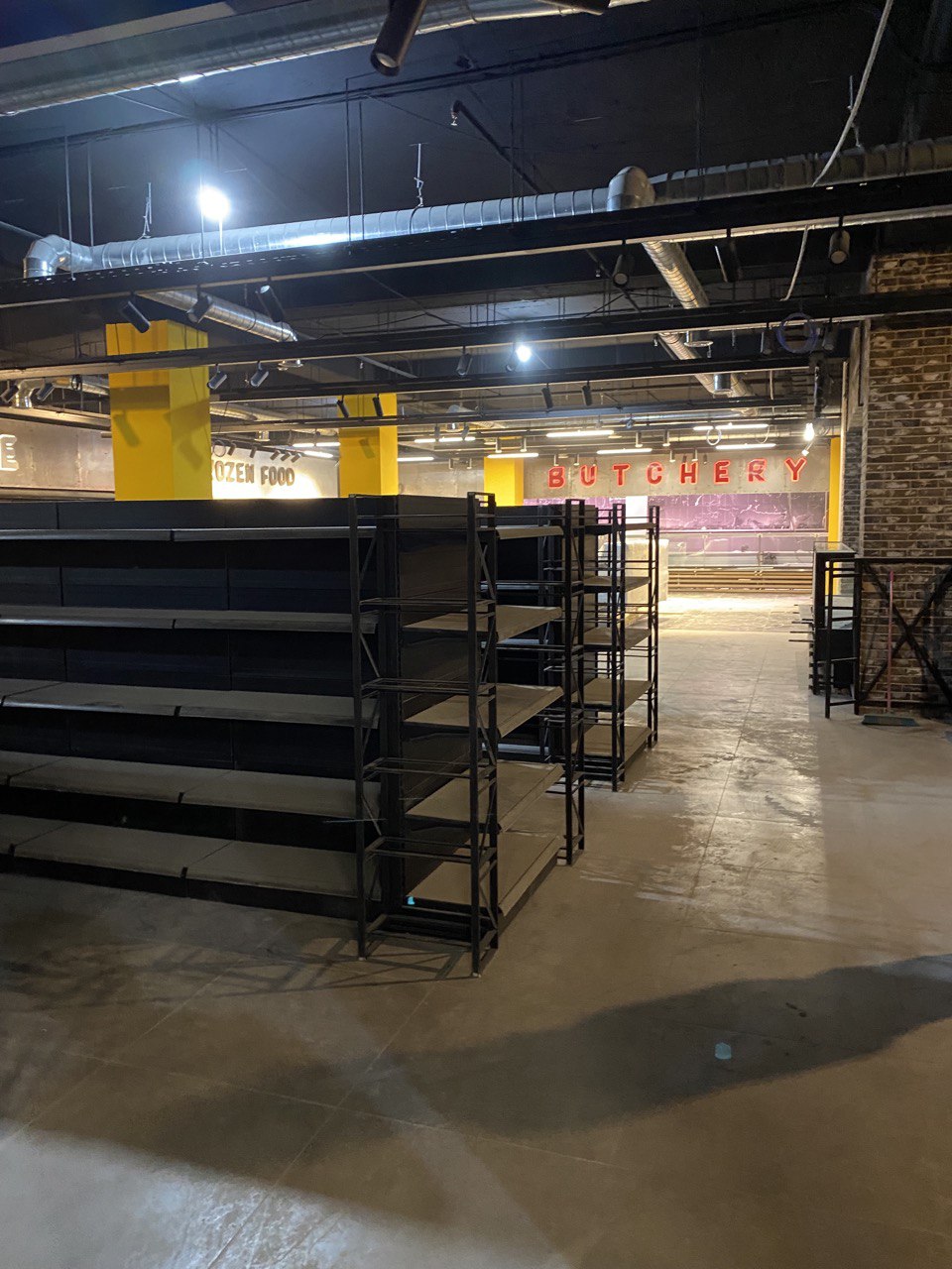 Artisan bakery island with stainless prep, display fridges, and warm lighting